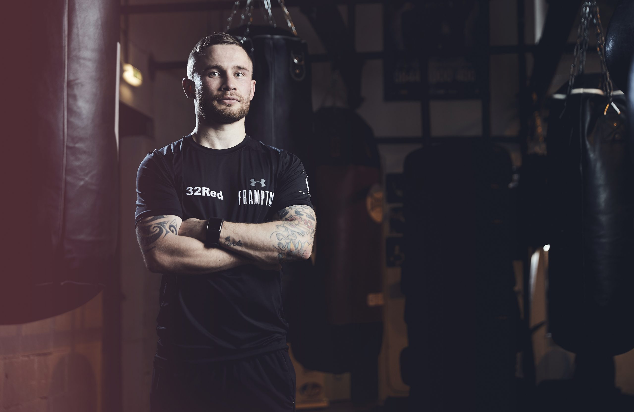 man in black top surrounded by boxing bags